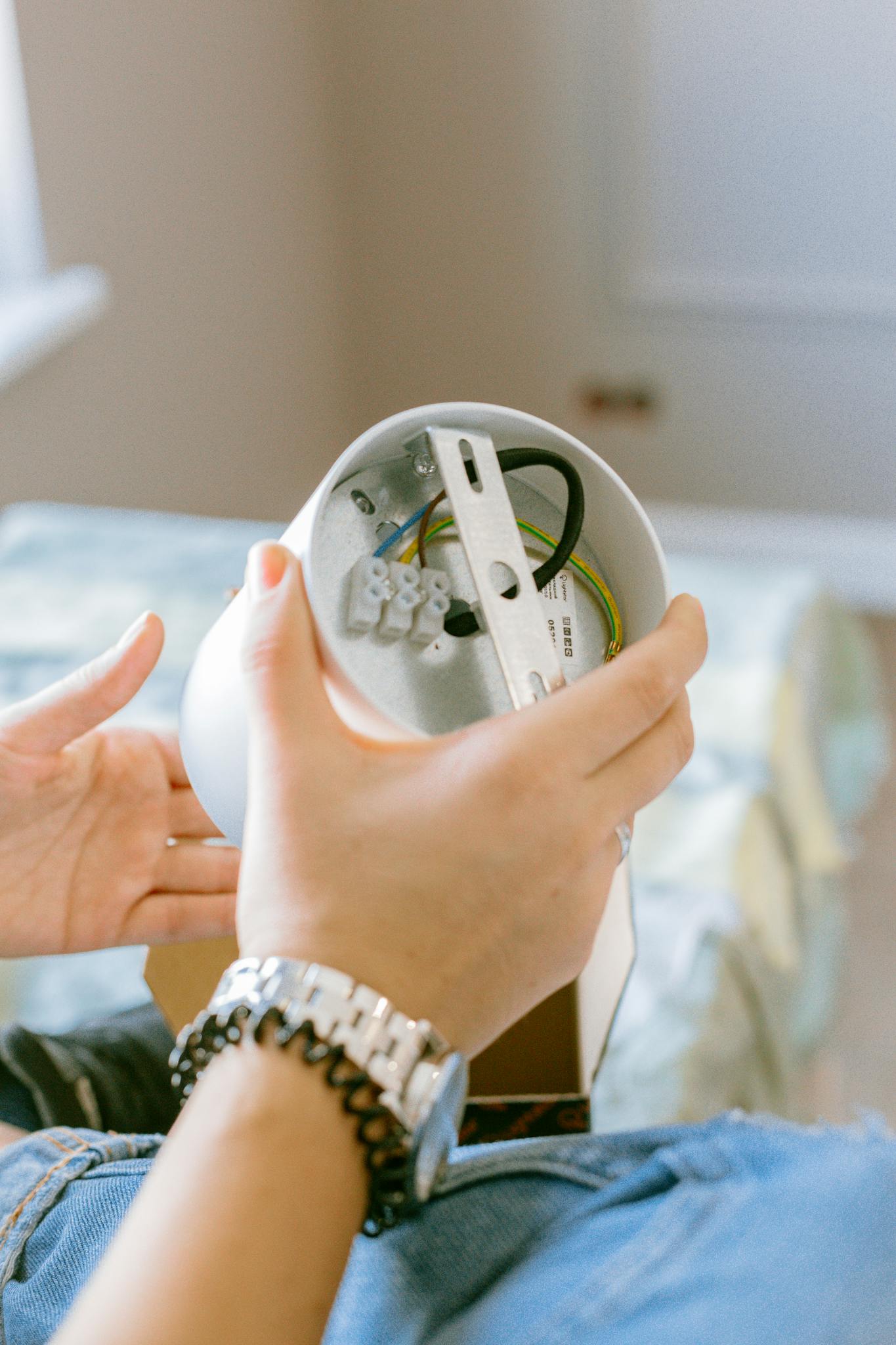 Close-up of a woman assembling a light fixture, showcasing home improvement and DIY skills.